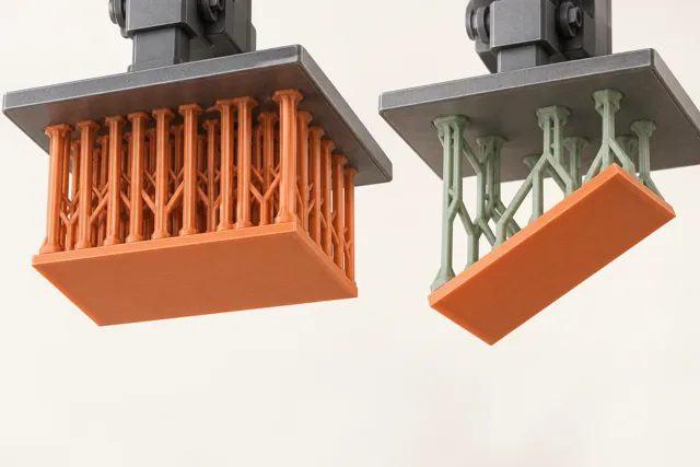 Flat and tilted orange parts connected by supports to overhead build platforms.