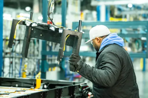 A GM worker uses a manufacturing fixture on the factory floor.